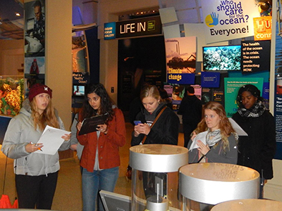 Four students taking notes at museum