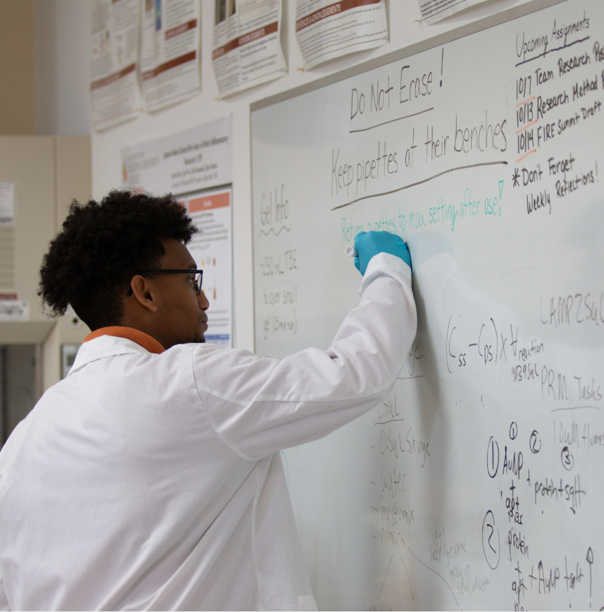 student in lab coat writing equations
